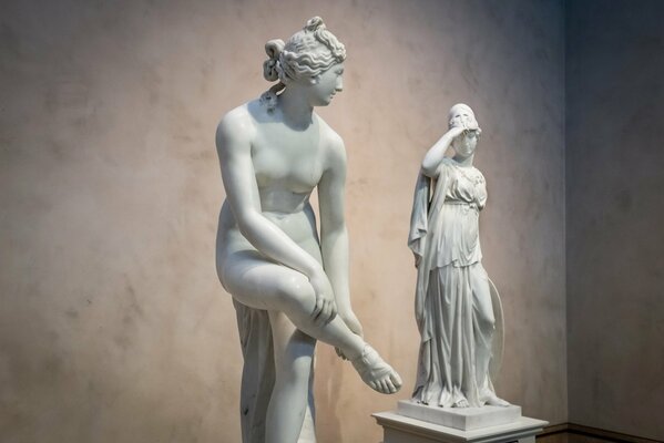 Due sculture di donne su sfondo muro vuoto