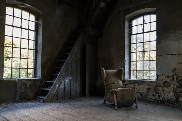 Ein verlassenes Haus mit einer Treppe zum Dachboden und Windfenstern