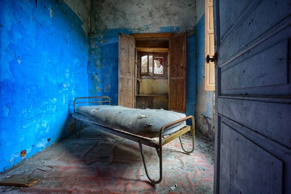 An abandoned hospital with an iron bed