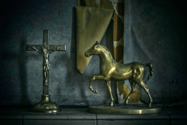 Against the background of the wallpaper that has moved away from the wall there is a statuette of a horse and a crucifix