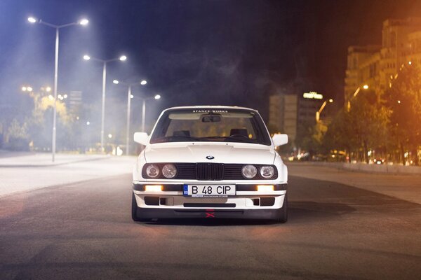 White BMW in the middle of the road at night