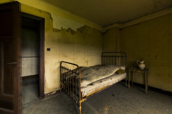 Stare łóżko w pokoju z otwartymi drzwiami