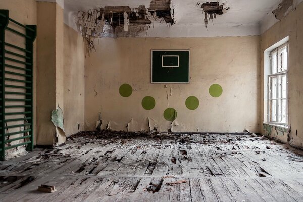 An abandoned gym with a broken basketball hoop