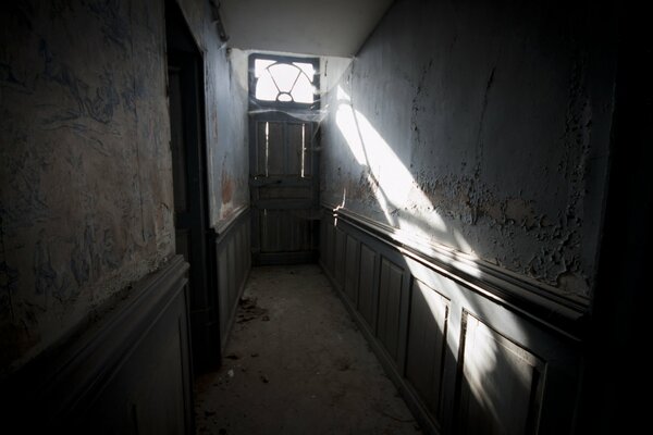 Una habitación larga y estrecha se ilumina a través de la puerta