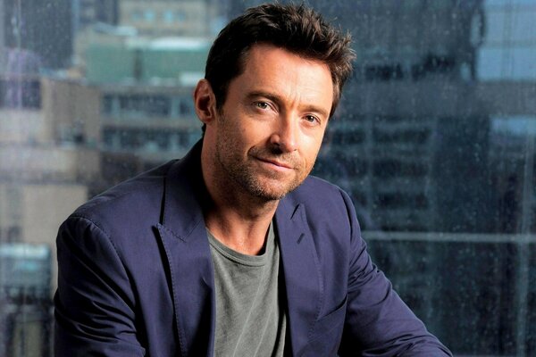 Hugh Jackman con una chaqueta malva en el fondo de la ventana