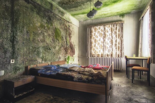 Habitación abandonada con cama y ventana