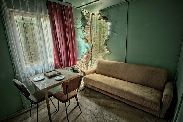 An abandoned house with a sofa and a table with chairs