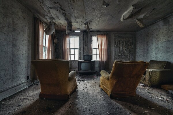 Opuszczony pokój z fotelami i telewizorami