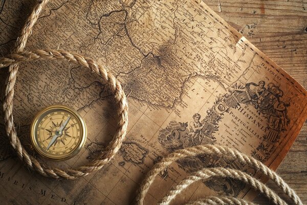 An old map with a rope and a compass lying on it