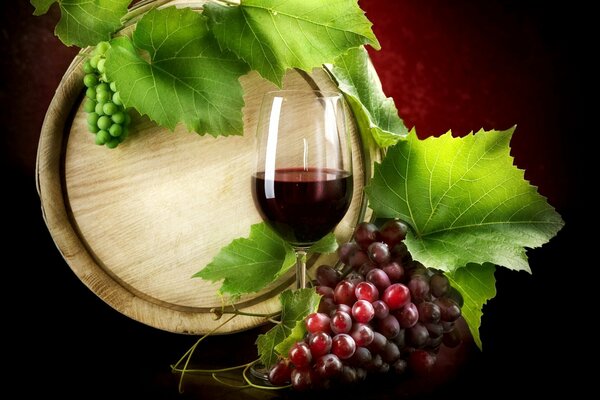Verre de vin sur fond de tonneaux et raisins