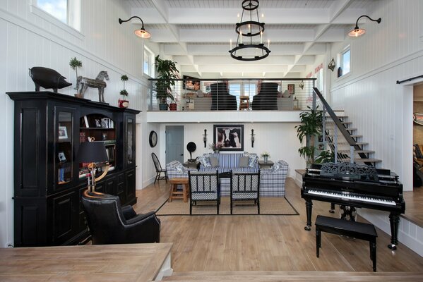 Enorme soggiorno con pianoforte nero vicino alle scale