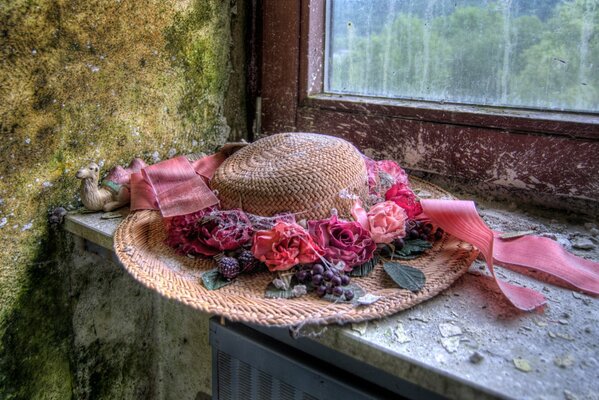 Chapeau avec des fleurs sur fond de fenêtre
