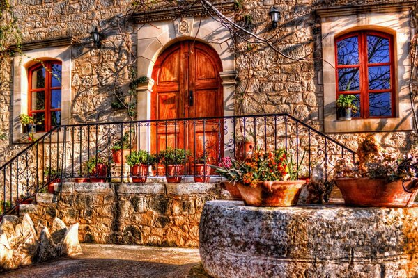 Porche d une maison en pierre avec des fleurs