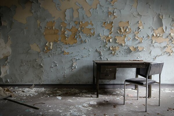 On the background of a shabby wall, a table and a chair