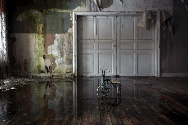 Pusty pokój bez tapety, pośrodku stoi rower, drzwi są całkowicie zamknięte