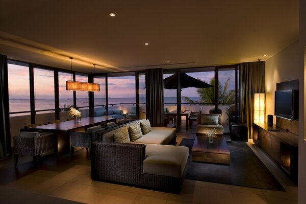 Sala de estar con amplias ventanas con vistas al mar de noche