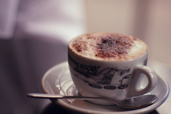 Cappuccino con schiuma in tazza bianca su sfondo sfocato