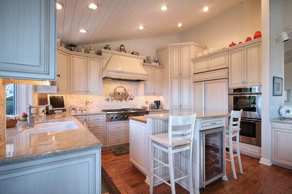 Cocina moderna de madera con sillas de patas altas en decoración blanca