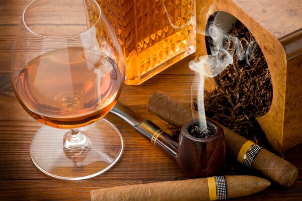 Sur la table, un verre de cognac et un cigare et un tube