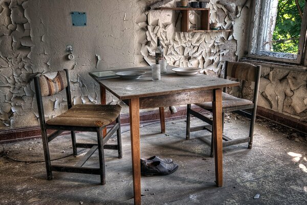 Sur le fond du mur de la cuisine, une vieille table et des chaises