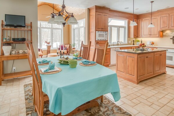 Wooden kitchen with high-backed chairs set at a table covered with a turquoise tablecloth
