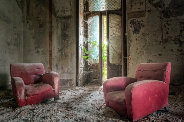 Two old dusty chairs in an abandoned building