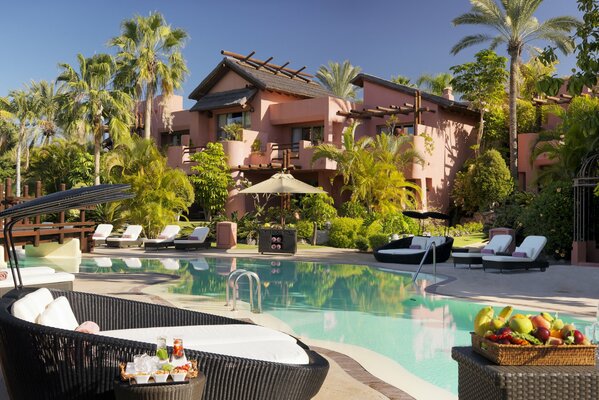 Swimming pool with sun beds on the background of a pitchfork with palm trees