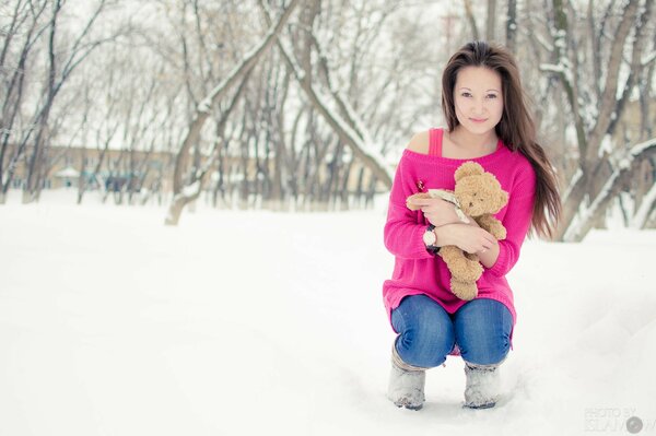 A girl with a teddy bear in winter