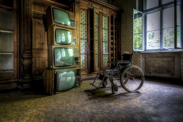 Silla de ruedas en la habitación con televisores