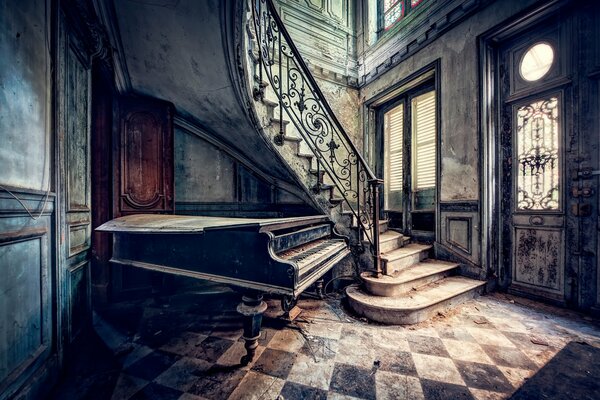 Vieux piano sous les escaliers dans une maison ancienne