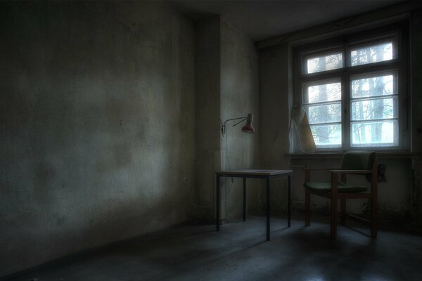 Chambre avec des murs nus et une table près de la fenêtre