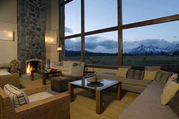 A cozy room with a fireplace and a mountain landscape outside the window