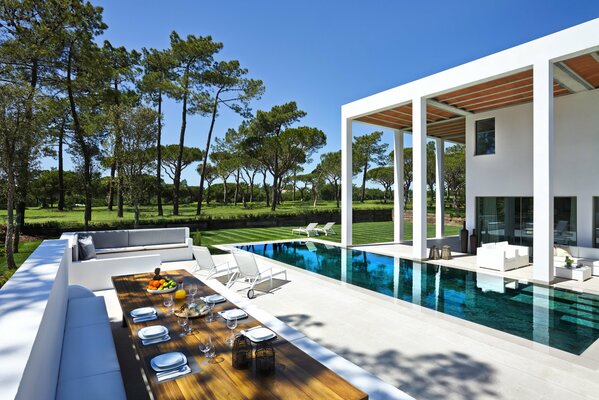 Bel intérieur de la maison avec piscine transparente. Autour de la piscine canapés, chaises longues