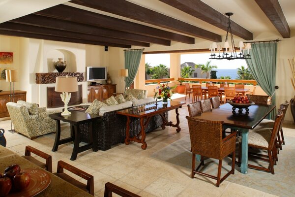 TV on the fireplace by the balcony with a vase. Interior design of the main house : tables, chairs, armchairs and a sofa 