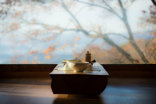 Table avec des tasses sur le fond de la vue d automne à l extérieur de la fenêtre