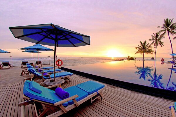 Piękny zachód słońca na basenie pod palmami nad oceanem