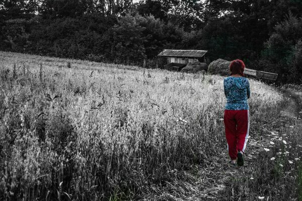 A woman walks along the road among a field of wheat