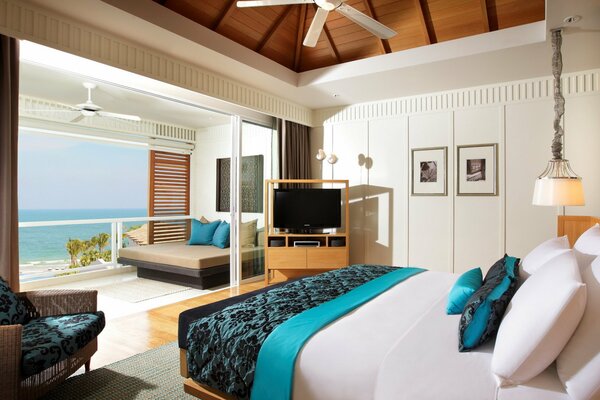 Urocza sypialnia w wiejskim domu z widokiem na ocean z podwójnym łóżkiem, telewizorem i wyjściem na balkon