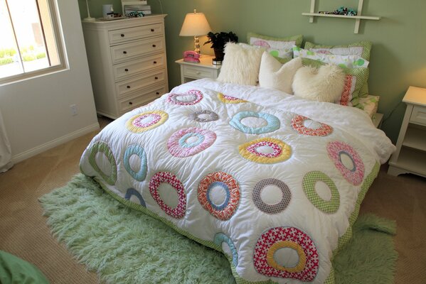 A bed in the bedroom with pillows and a colored blanket