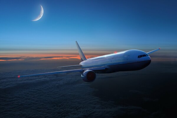 The plane flies above the clouds in the sunset sky