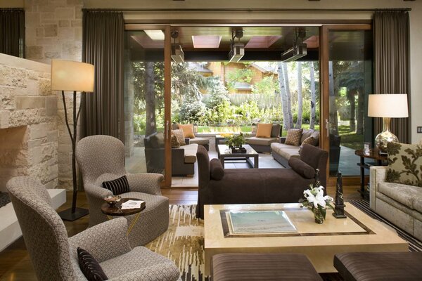 Living room with upholstered chairs, tables and a fireplace in a country ranch