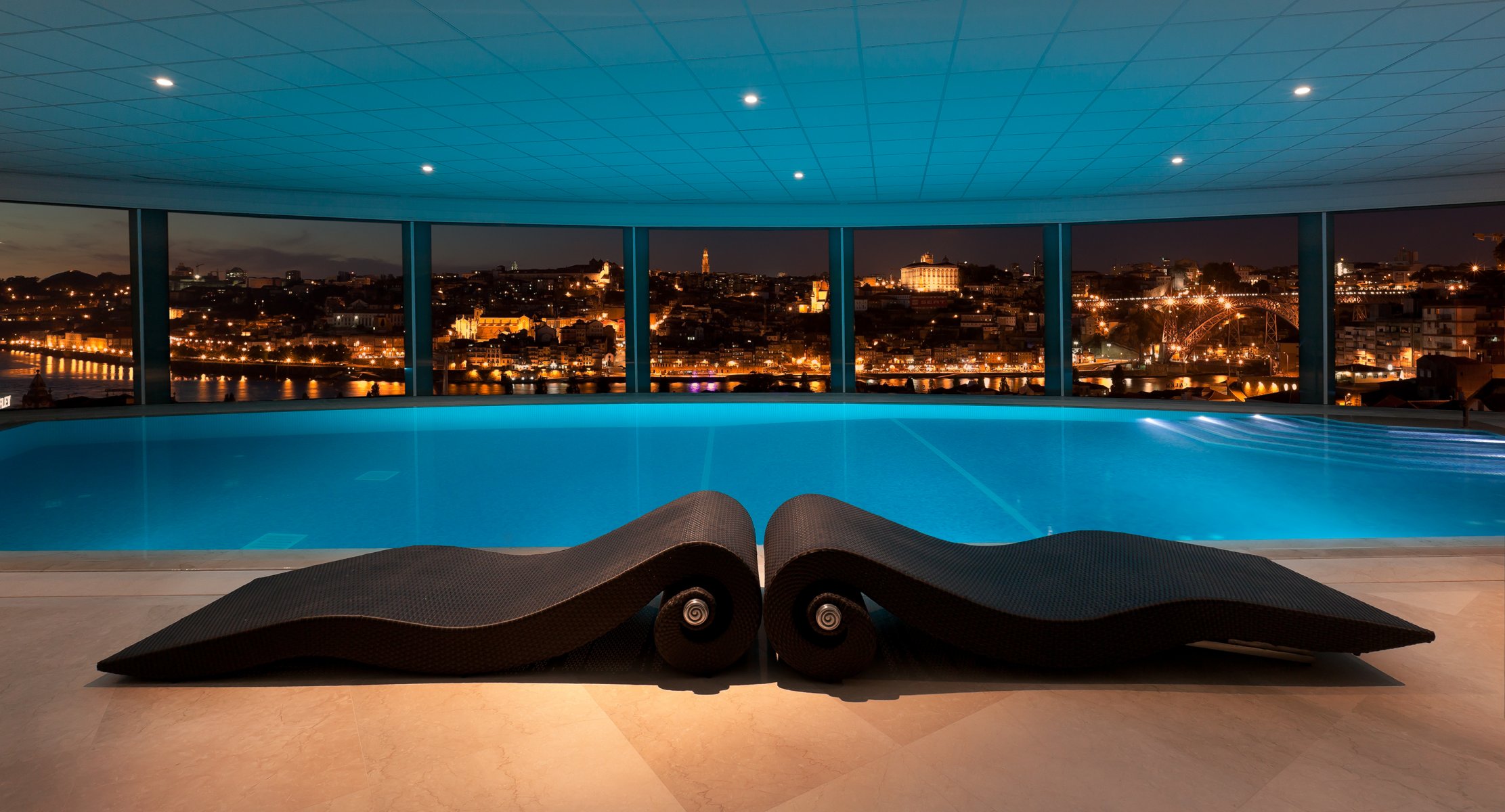 innenraum schwimmbad sonnenliegen fliesen aufhellung fenster panorama stadt nacht lichter fluss