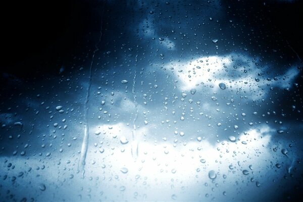 Regentropfen auf Glas vor bewölktem Himmel Hintergrund