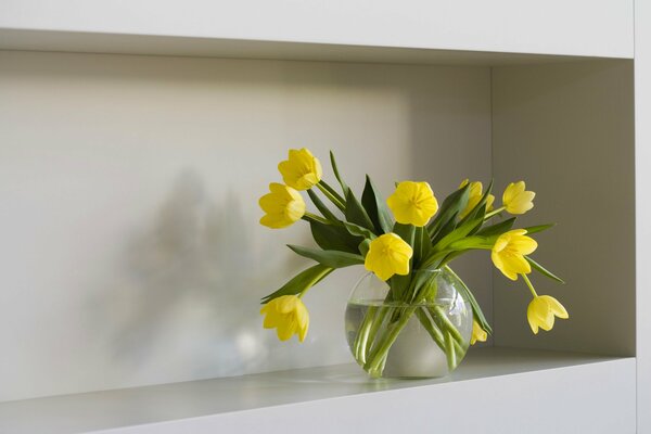 Yellow tulips in a vase on a shelf