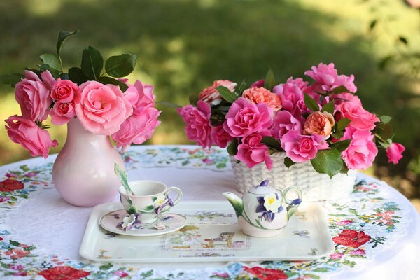 Vase avec roses, tasse et théière sur la table