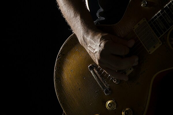 La mano de un hombre toca la guitarra