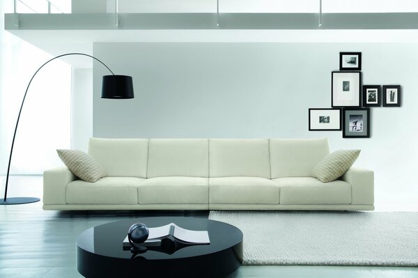 Salon z białą sofą i czarną lampą podłogową z ramkami na ścianie