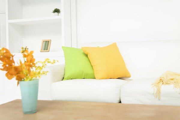 The stylish white sofa is decorated with yellow and green pillows