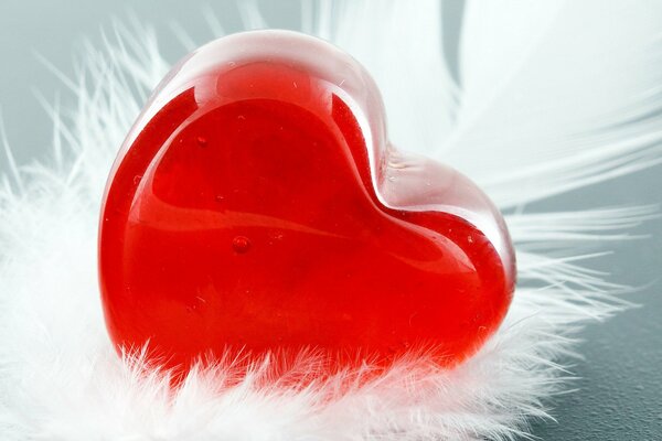 A red heart on a white feather