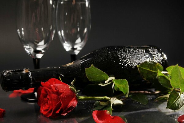 Bottiglia di champagne appannata con rosa e cena romantica